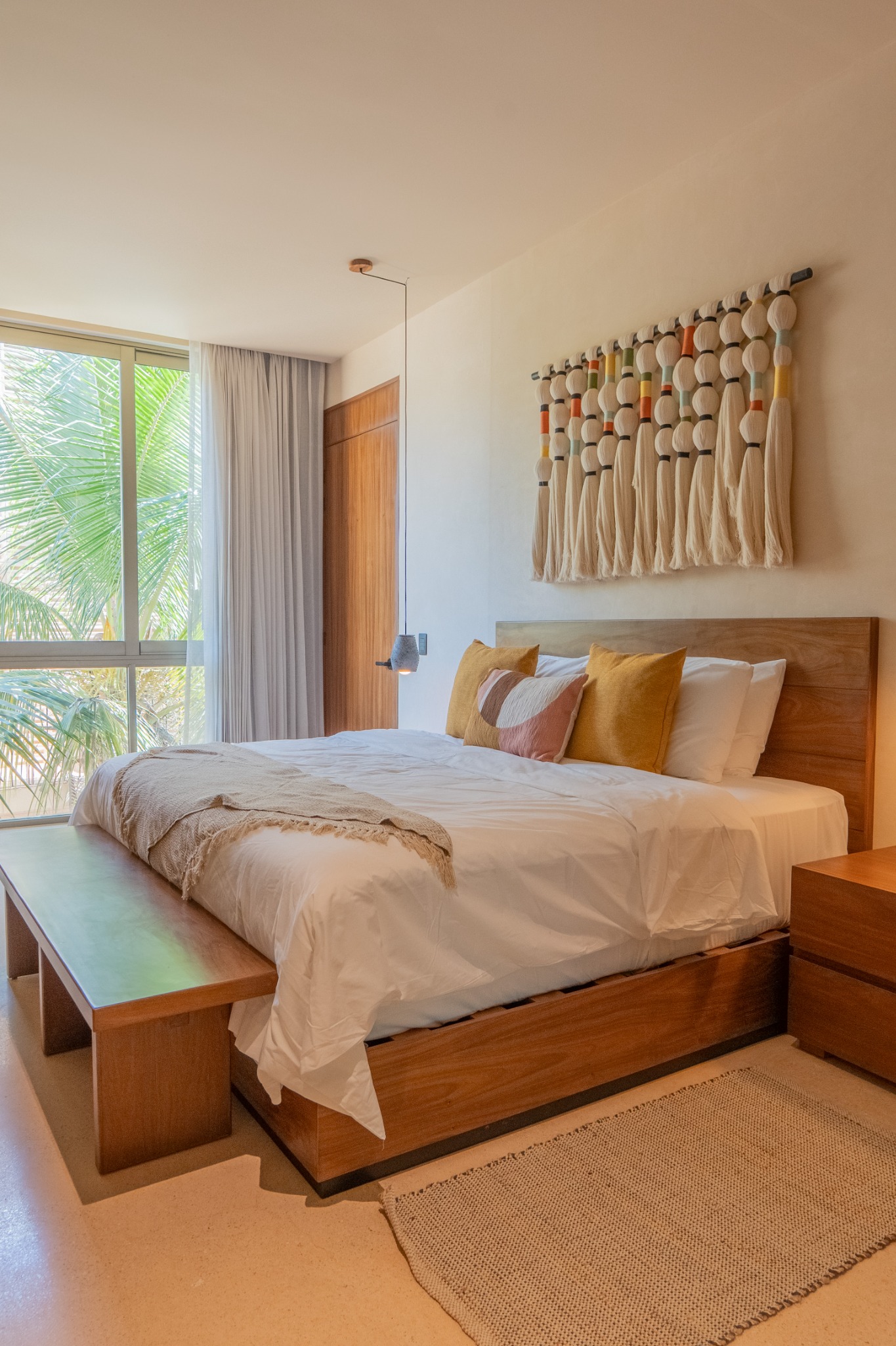 King bedroom with warm wood furniture and woven wall art